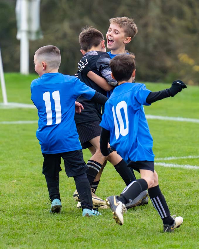 Junior league football goal celebration between teammates smiling faces happy boys