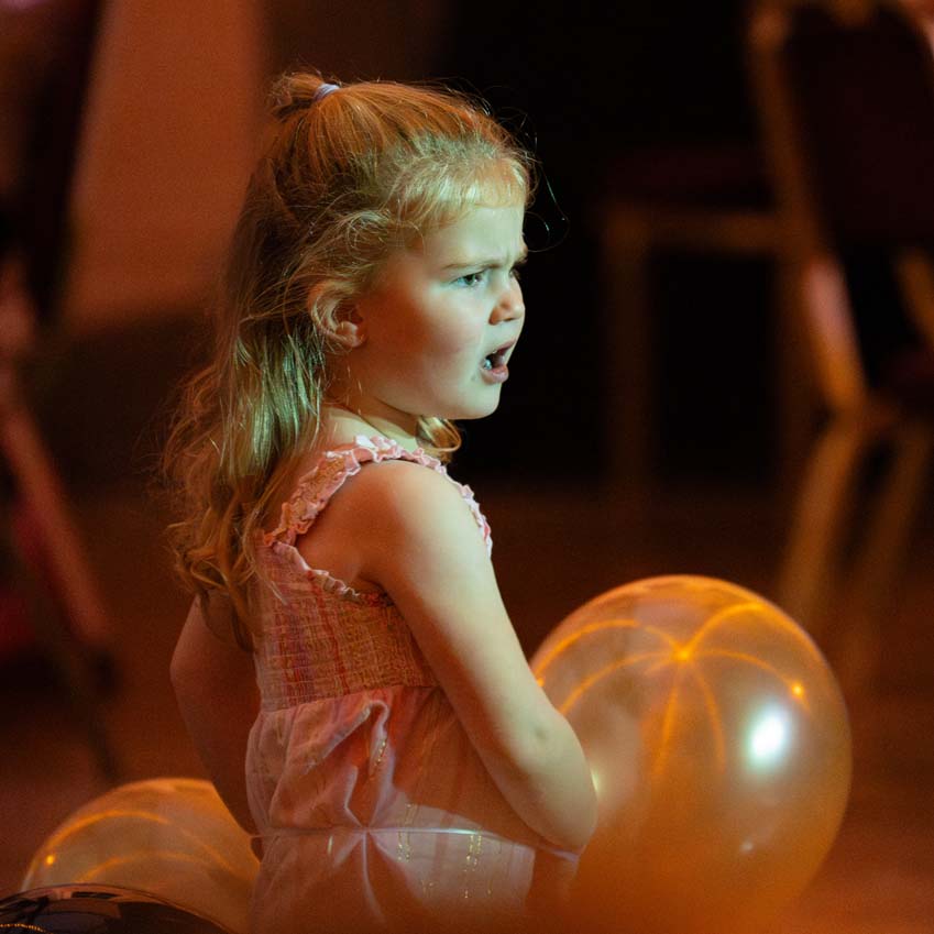 Young girl dancing at a birthday party with balloons and disco lighting