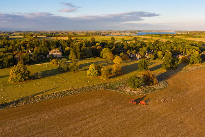 Conant Farming Quadtrac drilling winter crops in front of Lyndon Hall with Rutland Water in the background